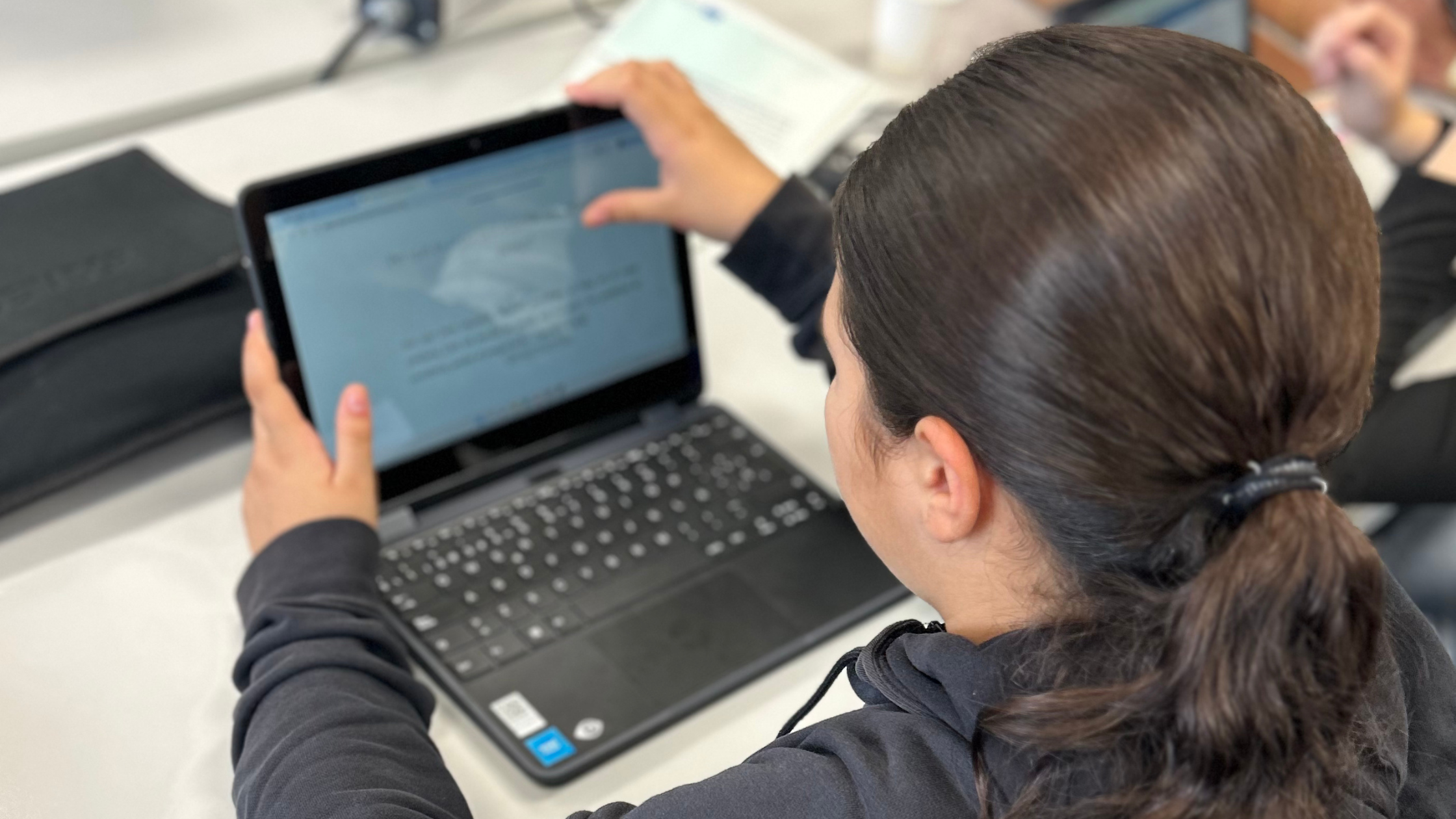 Auf dem Bild sieht man eine junge Person die vor einem Laptop sitzt.